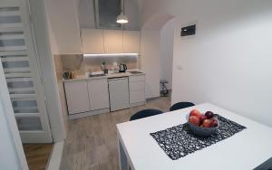 a kitchen with a table with a bowl of fruit on it at Apartman Tina in Novi Sad