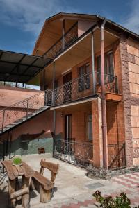 un edificio con balcón y banco de madera en Guest House VIP, en Borjomi