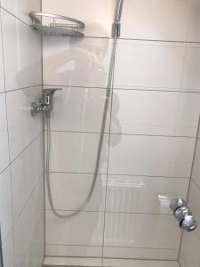 a shower with a hose on a white tiled wall at Gästehaus Sarker in Landsberg am Lech