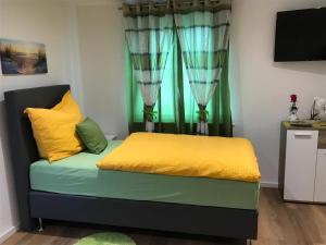 a bed with yellow and green pillows in a room at Gästehaus Sarker in Landsberg am Lech