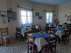 una sala da pranzo con tavoli e sedie blu e finestre di Villa Firostefani a Firostefani