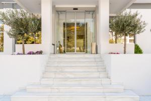 a white house with stairs and a glass door at Glyfada Riviera Hotel in Athens