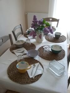 a table with plates and bowls and a vase of flowers at Au Nid Douillet in Seigy