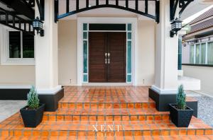 a front door of a house with two potted plants at Xent Pool Villa Ranong in Ranong
