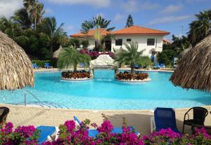 uma piscina num resort com cadeiras azuis e palmeiras em Bon Bini na Curacao em Willemstad