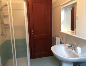 un bagno con lavandino e porta doccia in vetro di Cala Gonone - Casa della Pineta a Cala Gonone