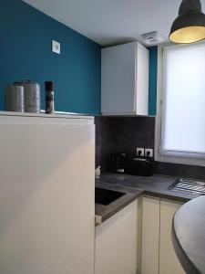 Ô Cosy في Longvilliers: مطبخ مع ثلاجة بيضاء وجدار ازرق