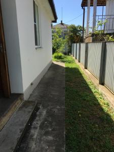 a sidewalk next to a white building next to a yard at Guest house Amza in Ochamchira