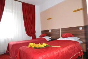 two beds in a hotel room with red sheets and yellow flowers at Hotel Premier Botosani in Botoşani