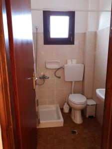 a bathroom with a toilet and a sink and a window at Katerina Apartments in Stalís