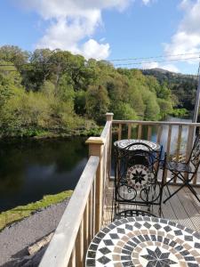 - une table et des chaises assises sur une terrasse donnant sur la rivière dans l'établissement The Black Sheep, à Glengarriff