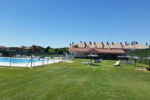 a resort with a swimming pool with people sitting on the grass at 6 Calle las Tuerces in Aldeamayor de San Martín