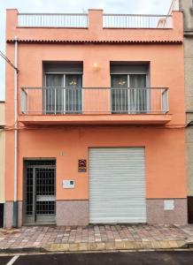 an orange building with a balcony and two garage doors at La Casa 5 de Gandia in Gandía