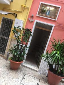 Casa vacanze Santa Maria في باري: مبنى وردي أمامه نباتات الفخار