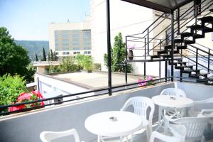 a patio with white tables and chairs on a balcony at Metekhi Vista in Tbilisi City