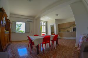 a dining room with a table and red chairs at Casa vacanze a 3 minuti a piedi dal mare in Messina