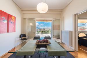 アテネにあるATHENStay Penthouse Suiteのダイニングルーム(ガラステーブル、緑の椅子付)