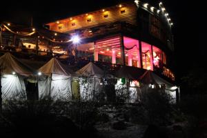 a building with tents in front of it at night at Dzajicaa Buk Rooms - Noahs Ark in Konjic