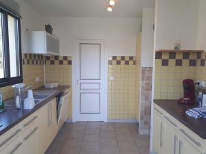 cocina con azulejos amarillos y puerta blanca en LOGIS de la CAVE, en Daglan