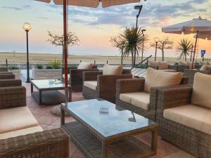 a patio with wicker chairs and tables with the ocean in the background at Hotel Karibe in Bibione