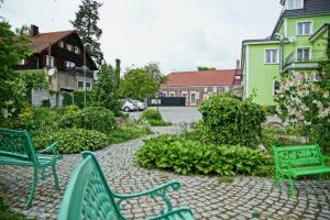 two green benches sitting in the middle of a garden at Hotel Sen in Świebodzin