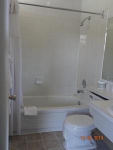 a bathroom with a tub and a toilet and a sink at Hospitality Inn in Kamloops