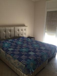 een slaapkamer met een bed met een blauwe en groene deken bij VILLA RYAD SAIDIA in Saidia 