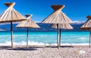 a group of straw umbrellas on a beach at Villa Valis in Baška