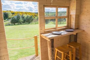 Cabaña con mesa, 2 taburetes y ventana en Little Lochan Lodge en Glenfarg