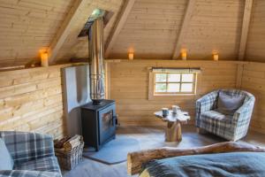 a living room with a stove in a log cabin at Little Lochan Lodge in Glenfarg