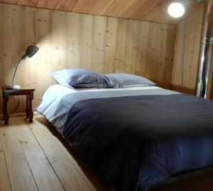 a bed in a room with a wooden wall at Gîte la ferme de Baffour in La Chaise-Dieu