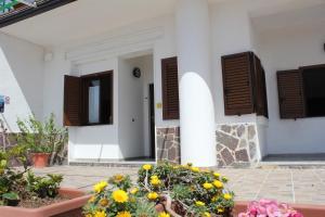 a white building with brown shuttered windows and flowers at La Meriggia B&B in Pisciotta