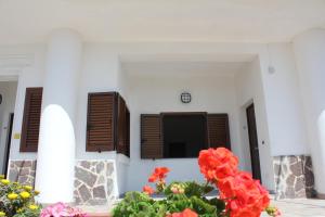 a white building with brown shutters and flowers at La Meriggia B&B in Pisciotta