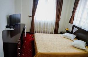 a bedroom with a bed and a television and a dresser at Hotel Sorelo in Piteşti