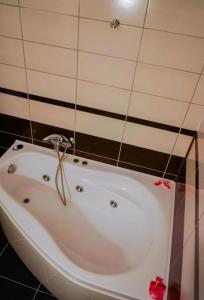 y baño con bañera blanca y azulejos negros. en Hotel Sorelo, en Piteşti