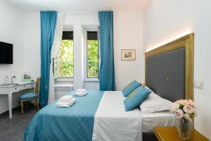 Cette chambre comprend un lit avec des rideaux bleus et un bureau. dans l'établissement Art Atelier Borgo, à Rome