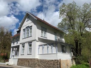 a white house with white windows and a stone wall at das weisse Haus am Fluss in Hahnenkopf