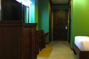 1 dormitorio con paredes verdes, 1 cama y TV en Chour Palace Hotel, en Mae Sai