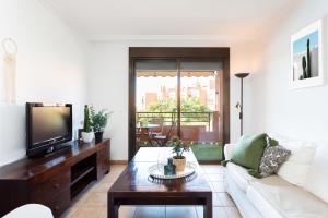 a living room with a white couch and a tv at Paradise palms Apartments in La Tejita