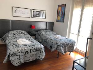 a bedroom with two beds and a table and a window at Musicisti House in Verona