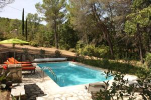 a swimming pool in a backyard with a patio furniture and an umbrella at Il Sole in Le Puy-Sainte-Réparade