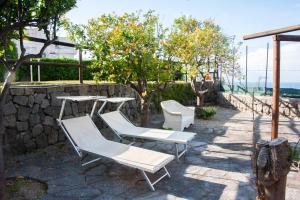 2 chaises et une table sur un mur en pierre dans l'établissement Casa Mo Ma vacanze Ischia, à Ischia