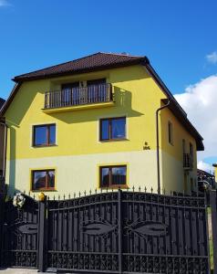 a yellow house with a black fence in front of it at Apartman Zatura in Vyšnie Šuňava