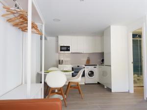 a kitchen with white cabinets and a table and chairs at Krm Suite Apartament in Calella