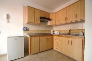 a kitchen with wooden cabinets and a white refrigerator at Apartamentos Andrea in Calera