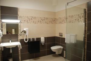 La salle de bains est pourvue de toilettes et d'une douche en verre. dans l'établissement The Originals City, Hôtel Cathédrale, Lisieux (Inter-Hotel), à Lisieux