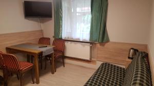 Pokój ze stołem, krzesłami i telewizorem w obiekcie Noclegi Silesia w Tychach