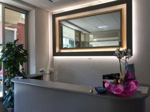 a mirror on a wall above a counter with flowers at Hotel Excelsior in Gabicce Mare
