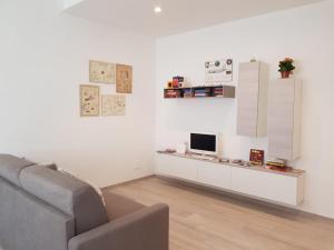 a white living room with a couch and a tv at Appartamento La Casetta in Arona