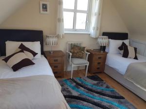 a bedroom with two beds and a chair and a window at St. Ellens in Inishbofin